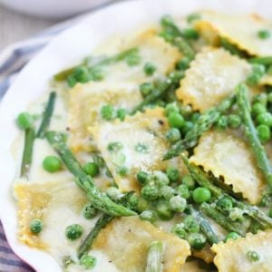 Ravioli with peas and asparagus in a baking dish.