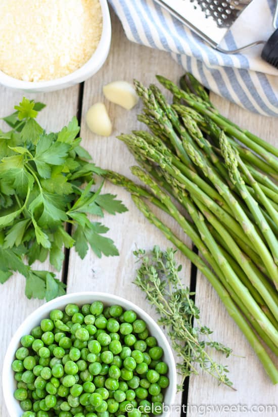 Asparagus, herbs, peas, and garlic on a wood board.