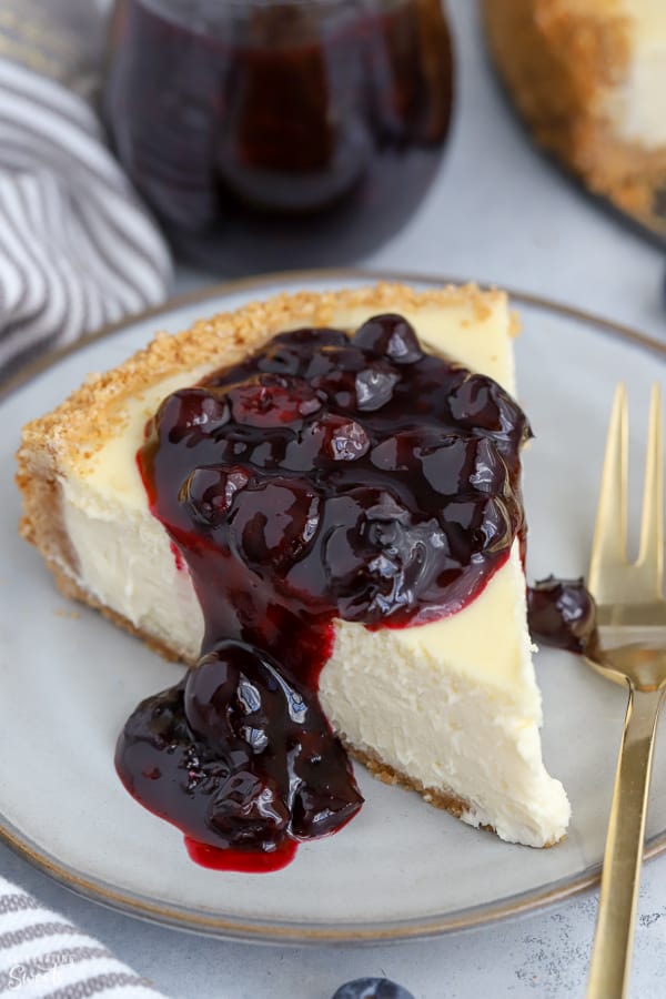 A slice of Greek yogurt cheesecake topped with blueberry sauce.