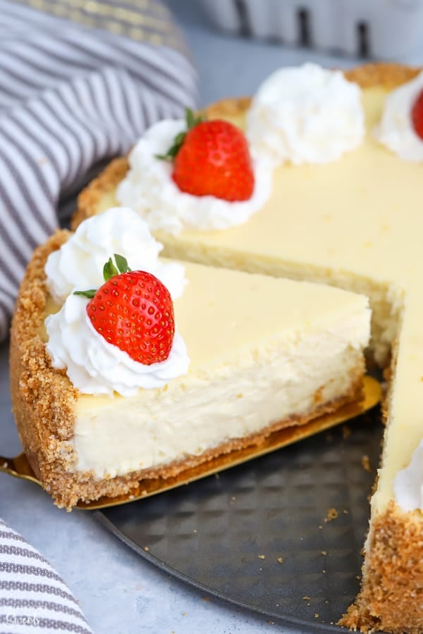 Greek yogurt cheesecake topped with whipped cream and fresh strawberries.