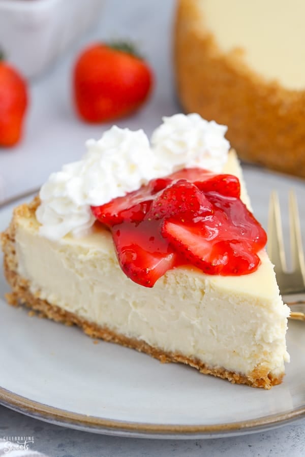 A slice of Greek yogurt cheesecake topped with strawberries and whipped cream.