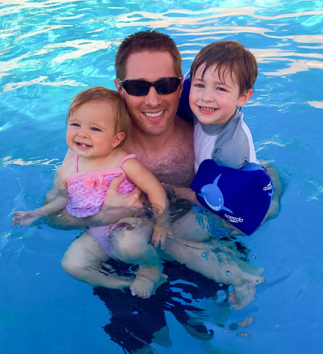 A man and 2 kids in a swimming pool.
