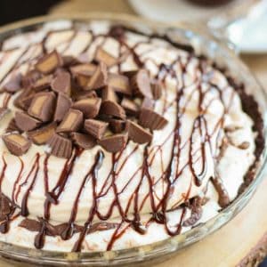 A close up of a peanut butter ice cream pie topped with fudge sauce.