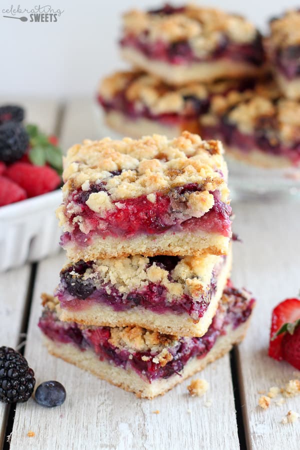 Stack of berry crumb bars with berries in the background.