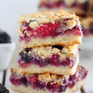 Three berry crumble bars stacked on top of eachother.