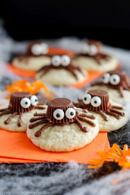 Sugar cookies decorated to look like a spider on an orange napkin.