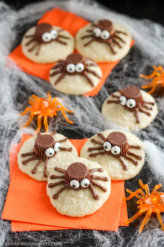 Sugar cookies decorated to look like a spider on an orange napkin.