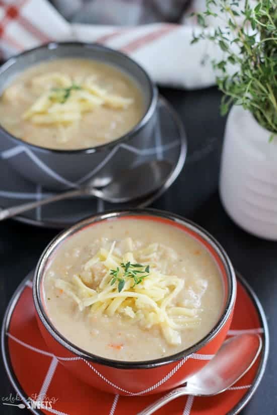 Cauliflower soup in red and grey bowls topped with white cheddar.