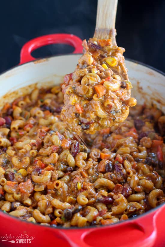 Chili mac in a skillet with a wooden spoon.