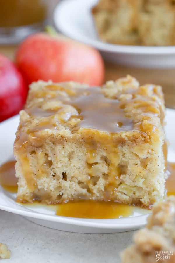 A slice of apple cake on a white plate topped with caramel sauce.