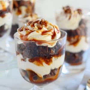 Brownie trifles in a glass dish topped with caramel.