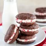 Stack of peppermint sandwich cookies with milk in the background.