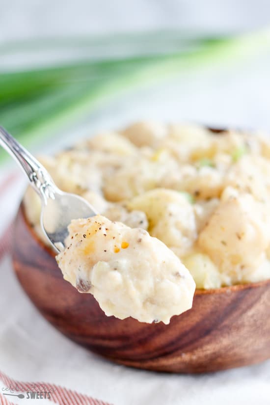 Creamy potatoes on a fork with a bowl of potatoes in the background.