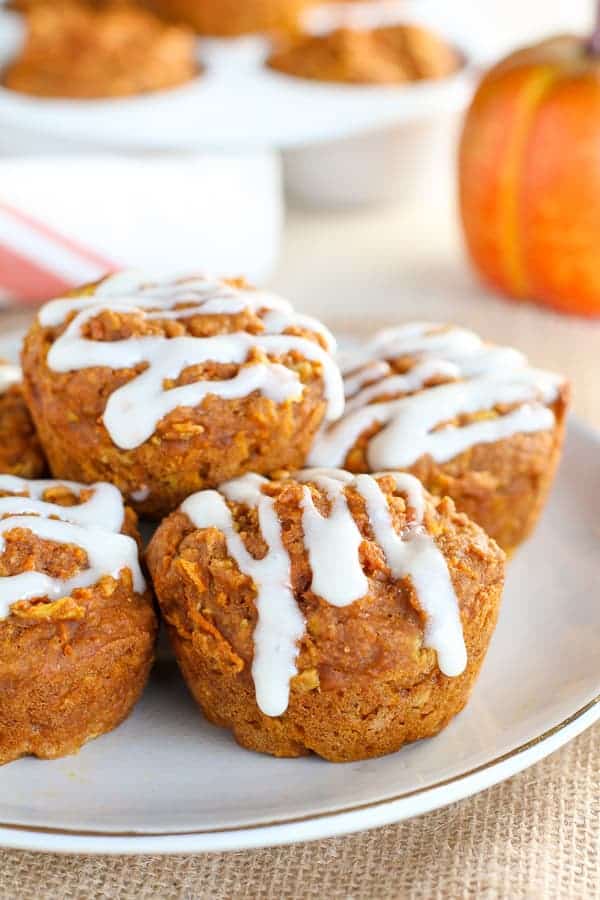 Healthy Pumpkin Muffins ona white plate with a pumpkin in the background.