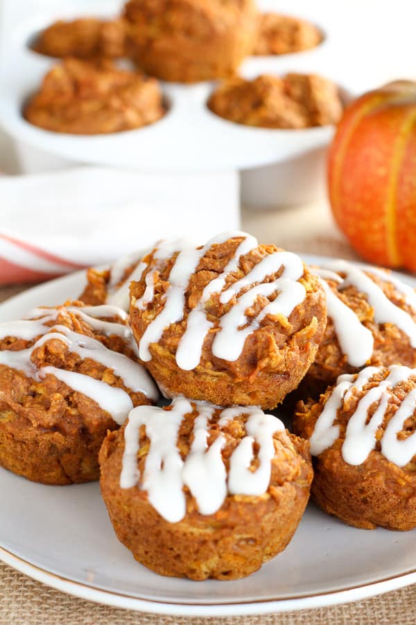 Plate of pumpkin muffins topped with white icing.