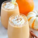 Pumpkin smoothie in a glass topped with whipped cream and cinnamon.