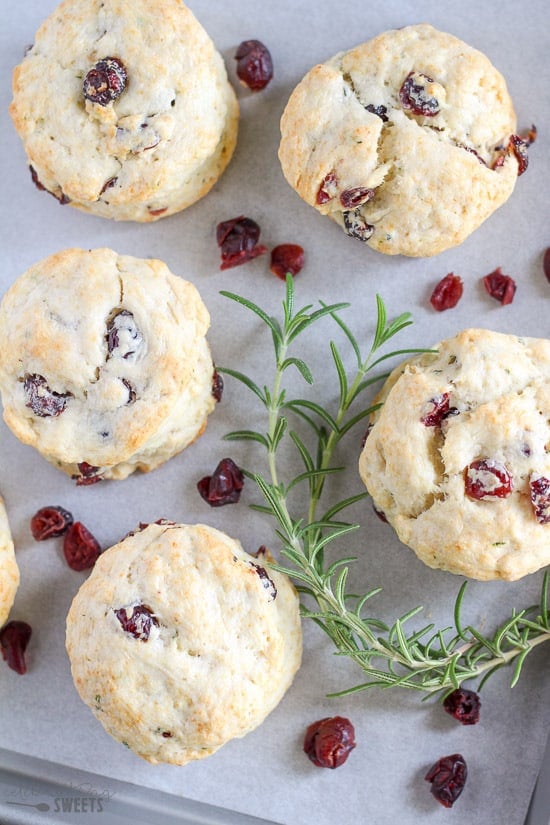Cranberry biscuits on a baking sheet garnished with rosemary.