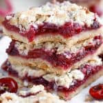 Stack of three almond crumble bars filled with cherries.