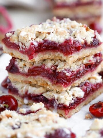 Stack of three almond crumble bars filled with cherries.