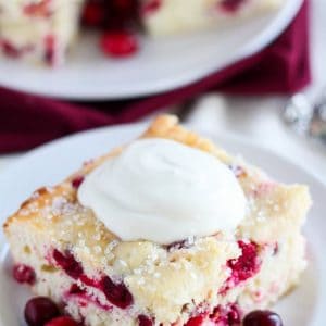 Cranberry cake on a white plate topped with yogurt.