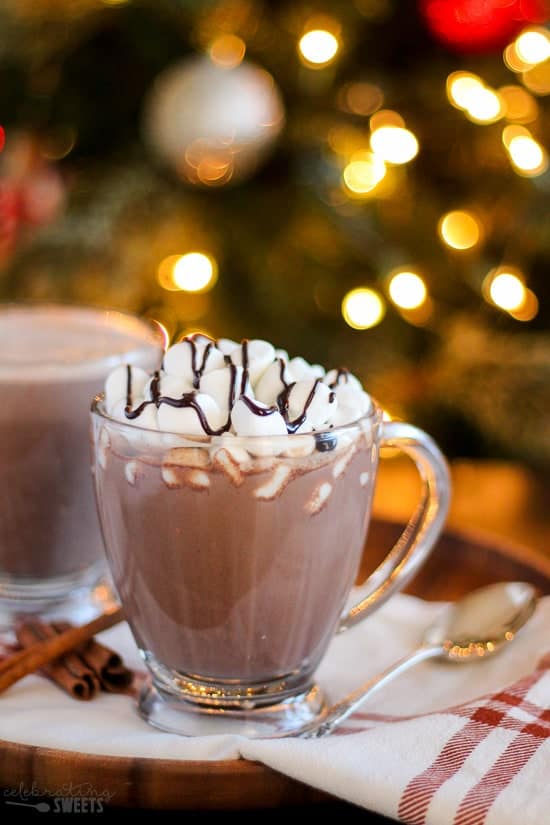 Glass of hot chocolate topped with marshmallows and a drizzle of chocolate sauce. 