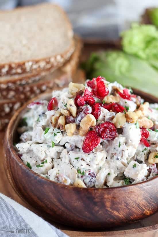 Chicken salad in a wooden bowl topped with dried cranberries.