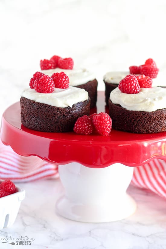 Small chocolate cakes with vanilla frosting and raspberries.
