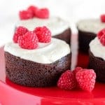 Small round cake topped with frosting and raspberries.