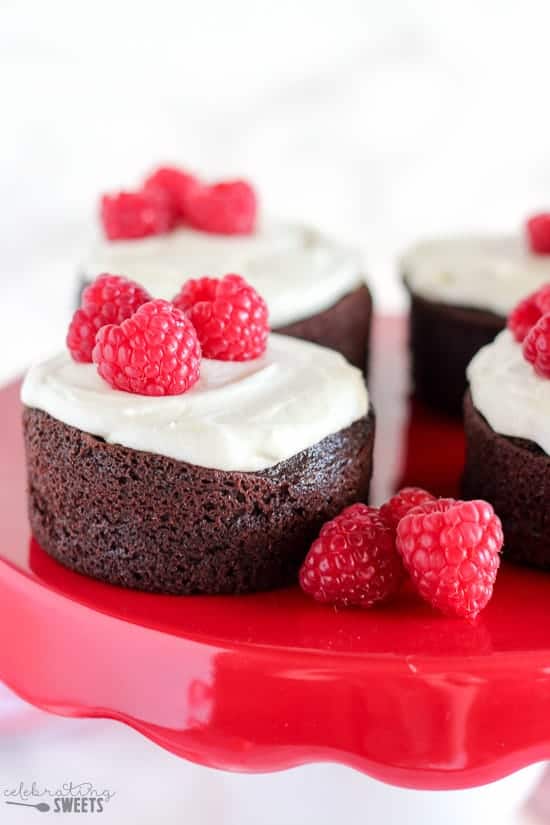 Small round cake topped with frosting and raspberries.