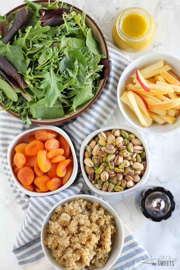 Bowls of lettuce, apples, apricots, and nuts.