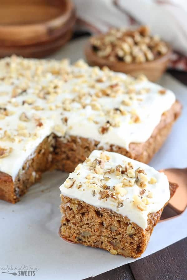 Square slice of carrot cake topped with white frosting.