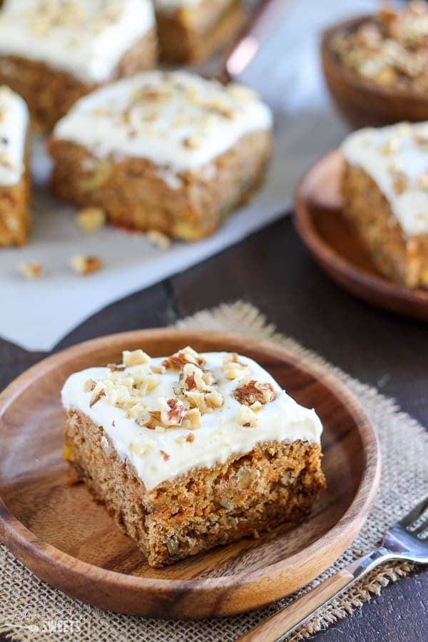 Slice of carrot cake on a wooden plate.