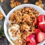 White bowl with granola, yogurt and strawberries.
