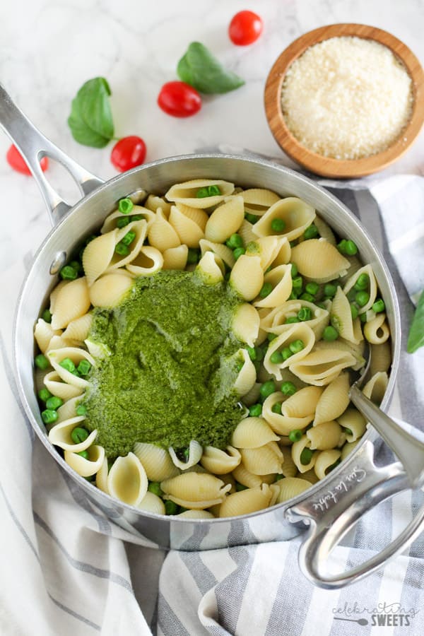 Saucepan of pasta shells with pesto and peas.