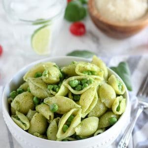 Bowl of pasta shells with pesto and peas.