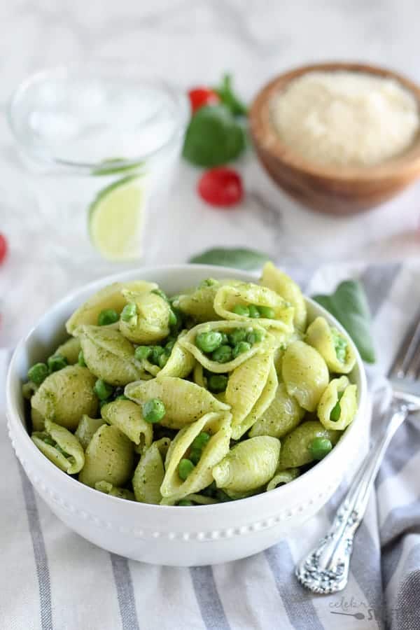 Bowl of pasta shells with pesto and peas.