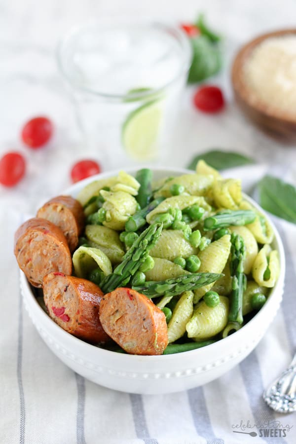 Bowl of pasta shells with sausage, pesto and peas.