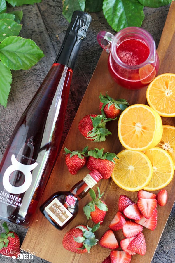 Wine, oranges, strawberries, on a board.