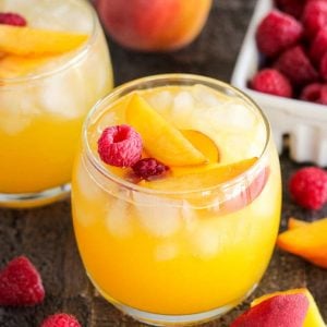 Peach margarita garnished with peaches and raspberries.