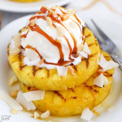 Grilled pineapple on a white plate topped with ice cream.