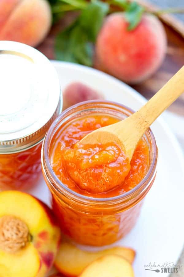 Closeup of peach jam with a wooden spoon. 