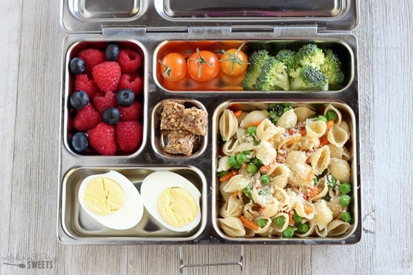 Lunchbox met pastasalade, groenten en bessen.