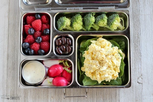 Lunchbox with egg salad, broccoli, berries, and radishes.