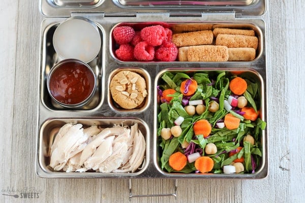 Lunchbox with salad, chicken, and cookies.