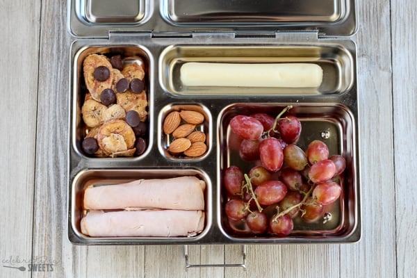 Lunchbox with grapes, turkey, trail mix, string cheese.