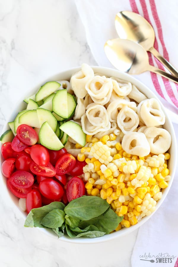 Bowl with tortellini, corn, tomatoes, zucchini, basil.