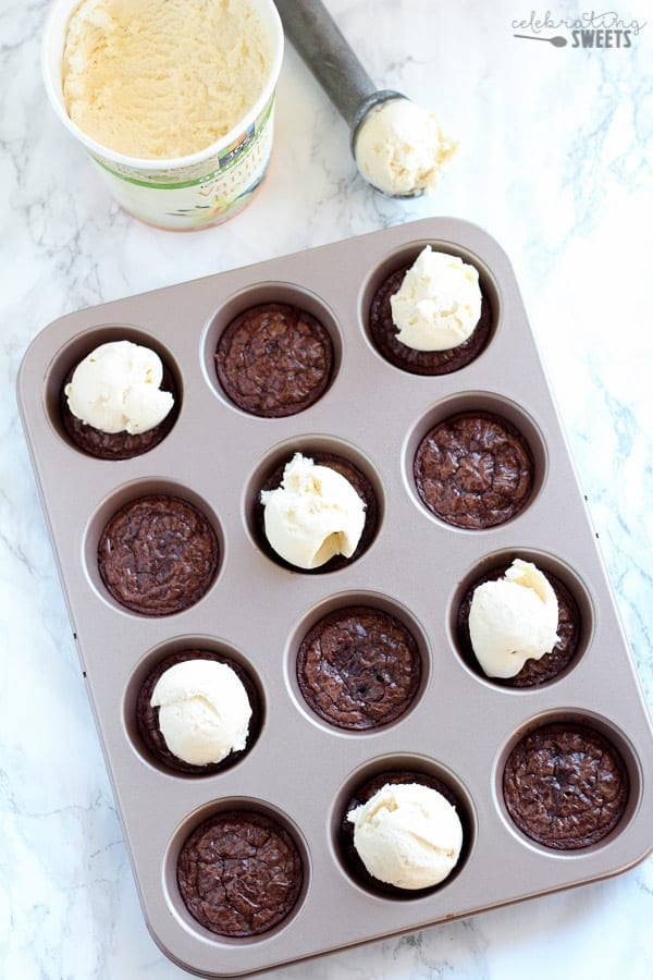 Brownies in a muffin tin topped with vanilla ice cream.
