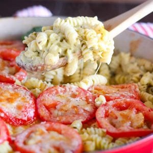 A close up of macaroni and cheese topped with sliced tomatoes.