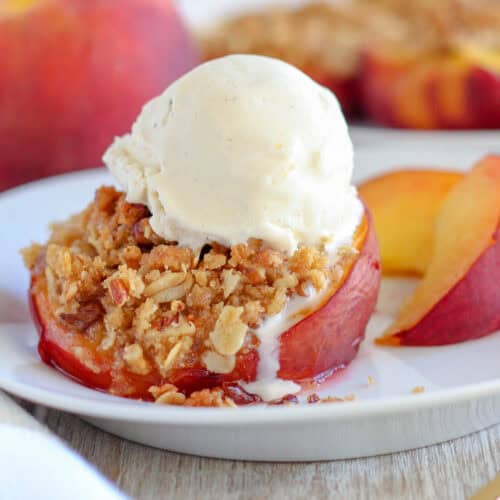 A stuffed peach on a white plate topped with a scoop of ice cream.