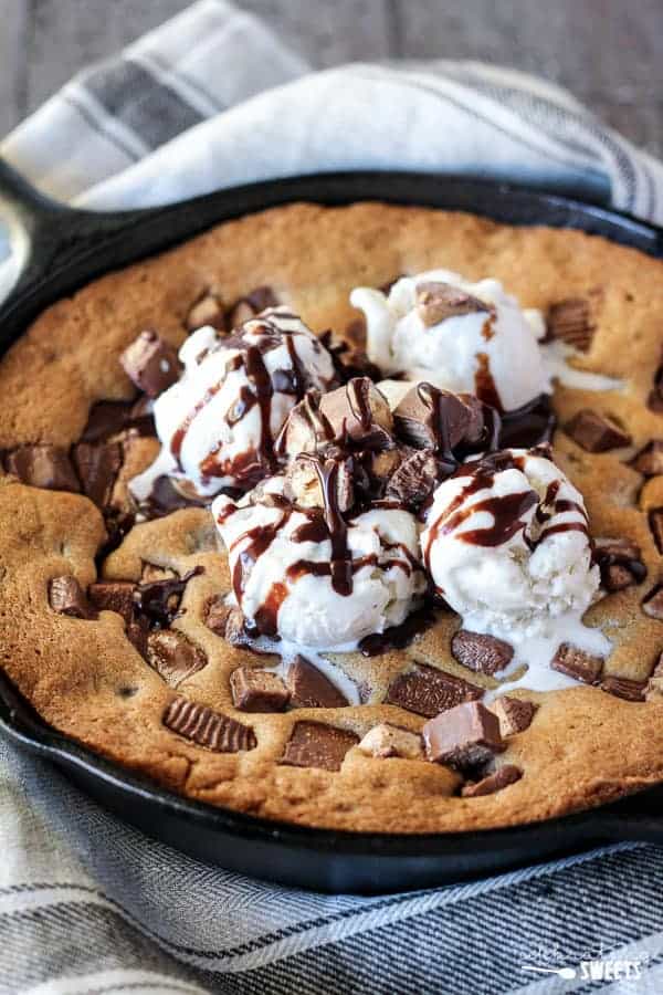 Skillet cookie topped with ice cream and chopped candy bars.